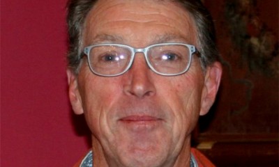 Ben Williams looks at the camera, wearing glasses, against a dark red background