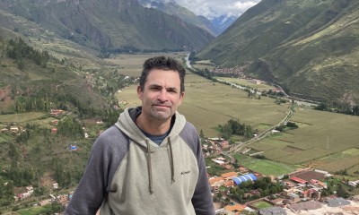 Robb sits on a stone wall overlooking a green valley