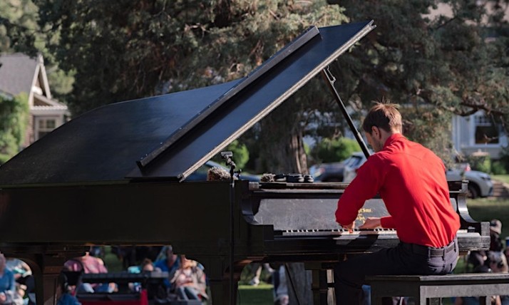 Person in a red shirt plays a piano outdoors